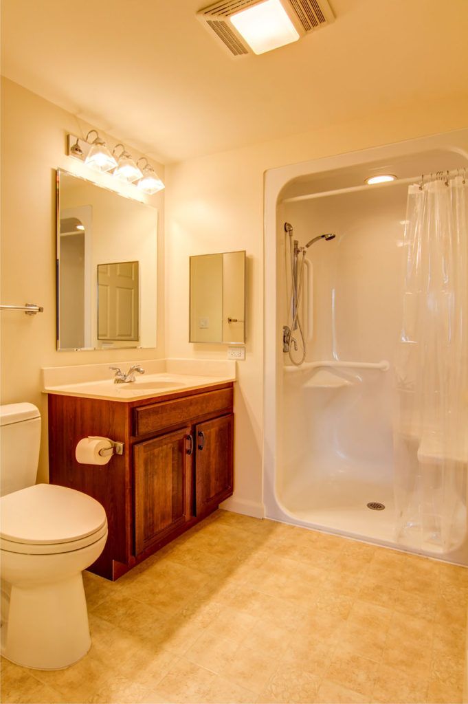 A clean and well-lit bathroom featuring a shower, vanity with sink, and toilet.