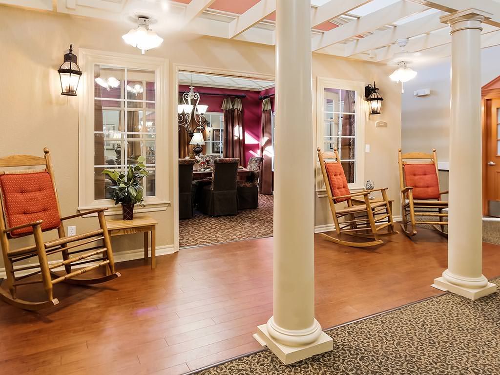 A cozy living area featuring rocking chairs, columns, and warm lighting.