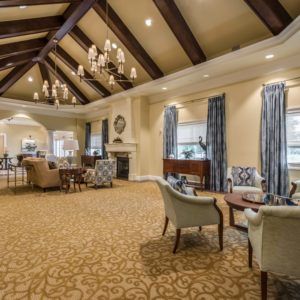A spacious and elegantly decorated lounge area with chandeliers and a fireplace.