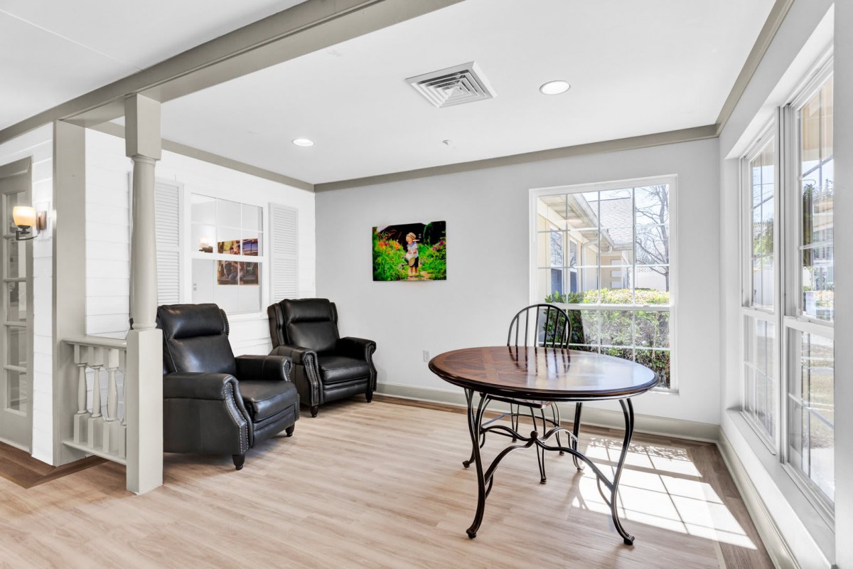 A modern living room with comfortable armchairs, a round table, and large windows allowing natural light.