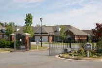 A view of a gated residential community with brick houses and a landscaped entrance.