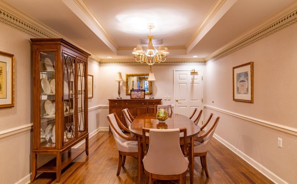 An elegant dining room with a chandelier, wooden table, and upholstered chairs.