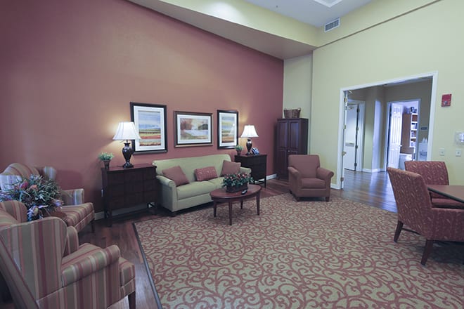 A cozy living room with a sofa, armchairs, and decorative artwork on the wall.