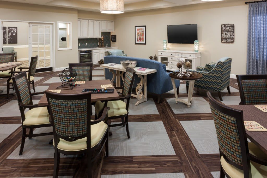 An open-concept living space featuring a seating area, dining table, and kitchen, with stylish furniture and a wall-mounted television.
