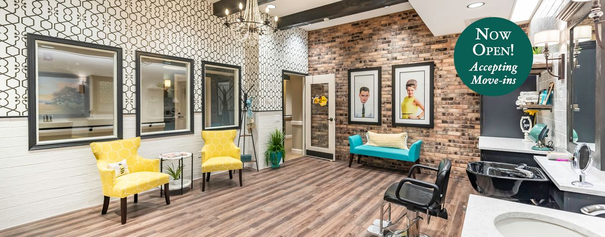 A stylish salon interior with modern decor, featuring a vibrant turquoise couch, yellow chairs, and a brick accent wall.