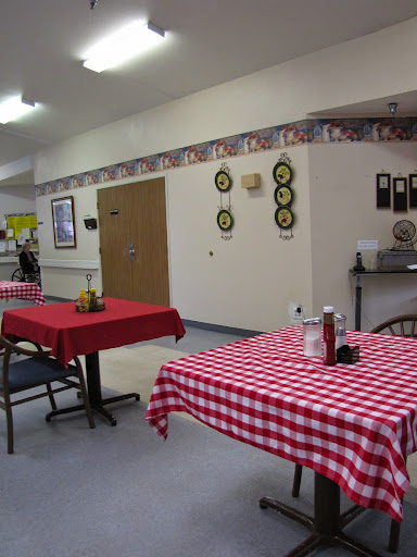 A cozy dining area featuring checkered tablecloths and condiments on the tables.