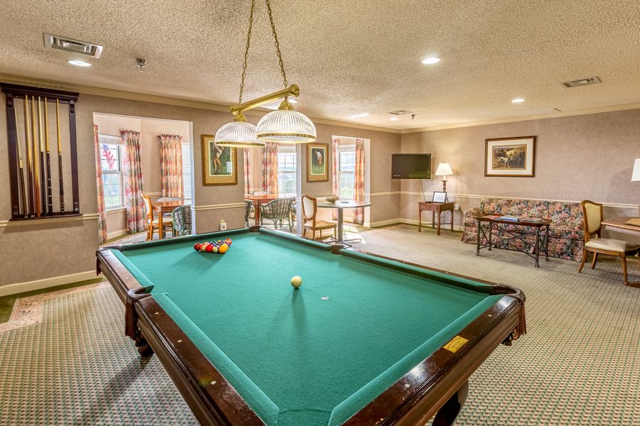 A cozy game room featuring a billiards table with overhead lighting.