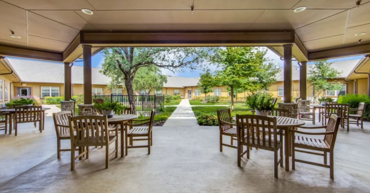 A tranquil patio with wooden chairs overlooks a garden path leading through lush greenery.