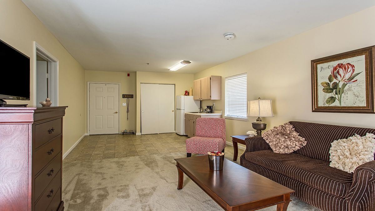 A cozy living space featuring a small kitchenette, a sofa, and an armchair with warm lighting.