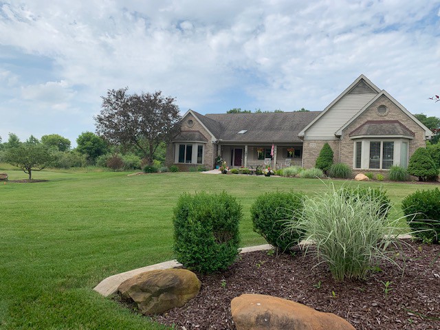 A suburban house with a well-maintained lawn and garden on a cloudy day.