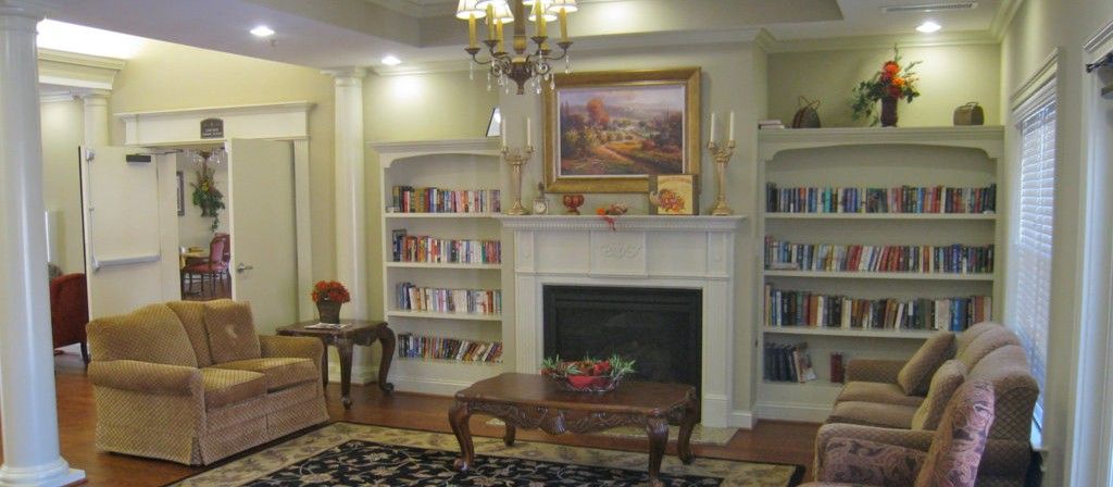 A cozy living room with bookshelves, a fireplace, and elegant decor.