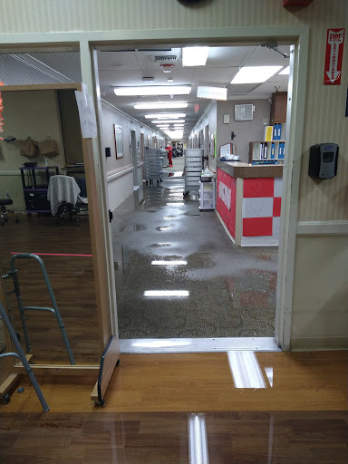 A view of a hospital hallway with wet floors, likely undergoing cleaning.