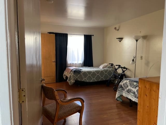 A cozy bedroom with a single bed, wooden flooring, and simple furnishings.
