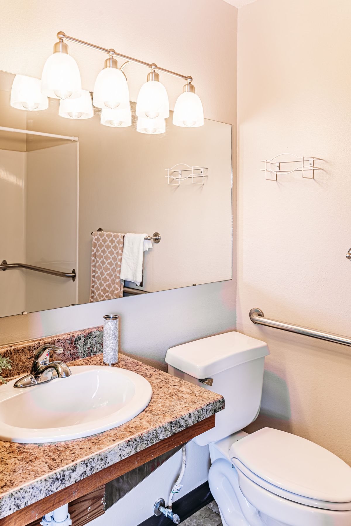 A clean and well-lit bathroom with a sink, mirror, and toilet.