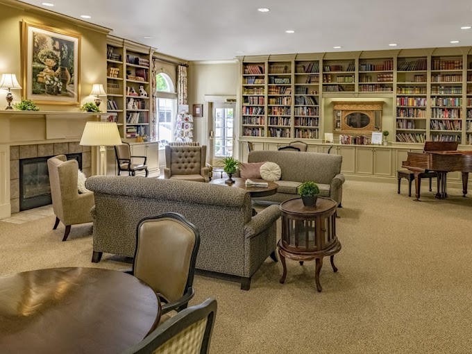A cozy living room with bookshelves, comfortable seating, and warm lighting.