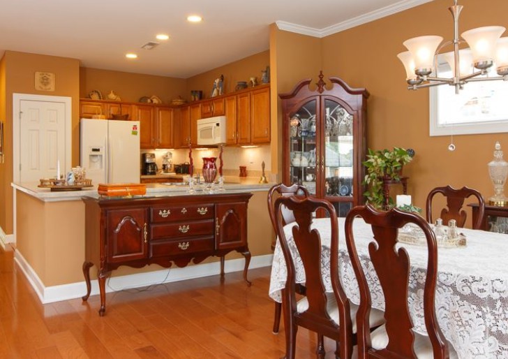 A traditional dining area featuring wooden furniture and a view of the adjacent kitchen.