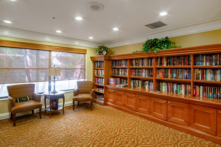 A cozy library room with a large wooden bookshelf and comfortable seating.