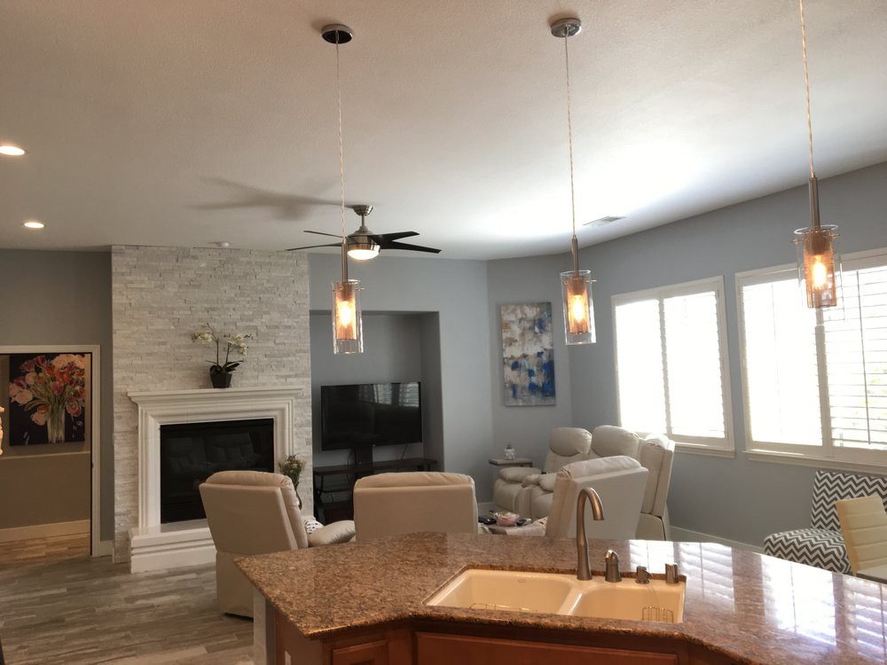 A modern living room with a fireplace, ceiling fan, and stylish seating area.
