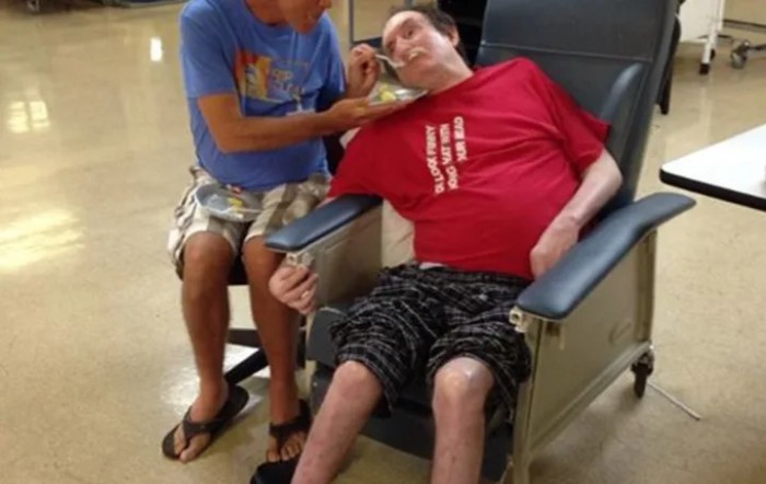 A caregiver assists a patient in a wheelchair at a healthcare facility.