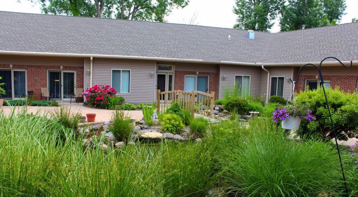 A residential building surrounded by a lush garden with various plants and flowers.