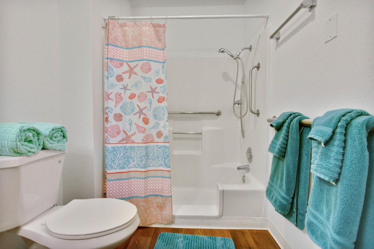 A neatly organized bathroom with colorful shower curtain and turquoise towels.