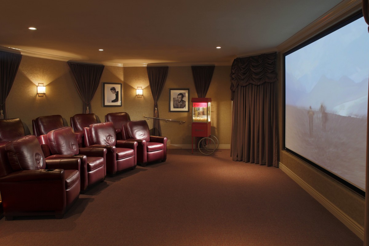 A cozy home theater with leather seating and a large projector screen.