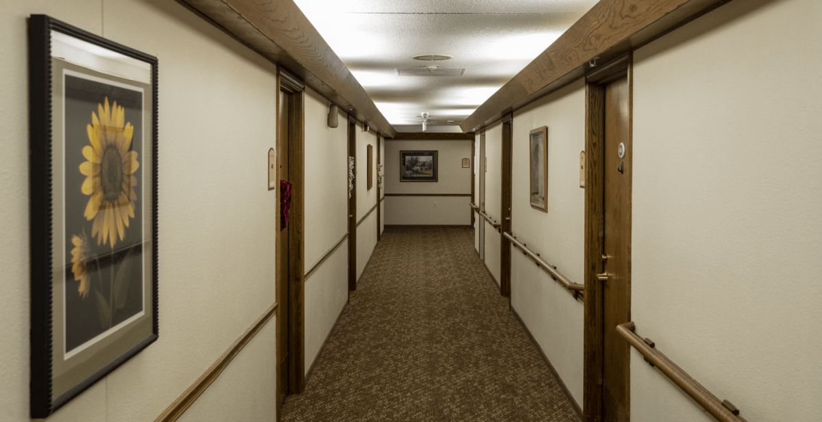 A long hotel hallway with doors on either side and a carpeted floor.