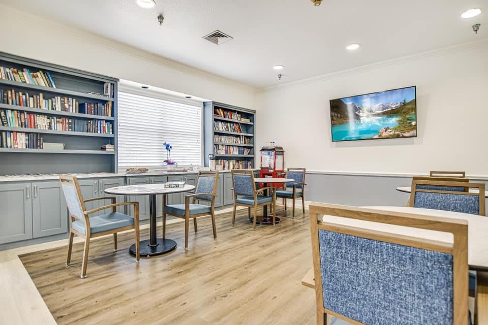 A cozy reading area with bookshelves, tables, and a television.