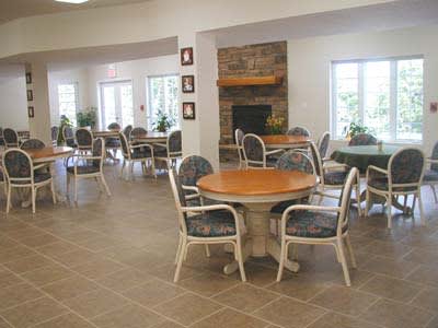 An indoor dining area with tables and chairs arranged around a central fireplace.