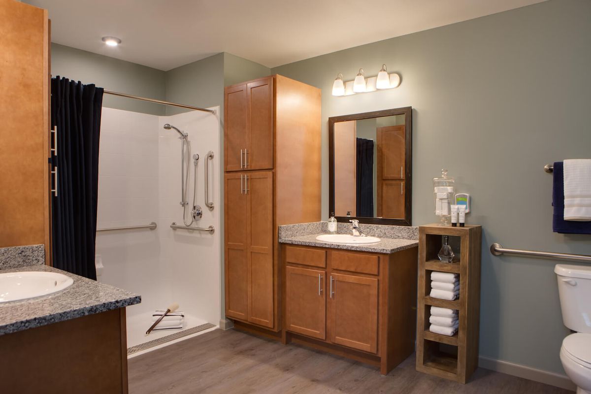 A modern bathroom with a shower, vanity, and wood cabinetry.