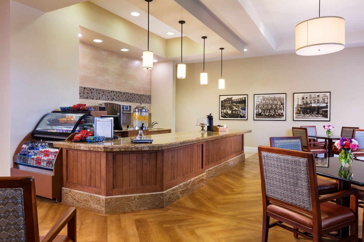 A modern indoor coffee station with a countertop, seating area, and ambient lighting.