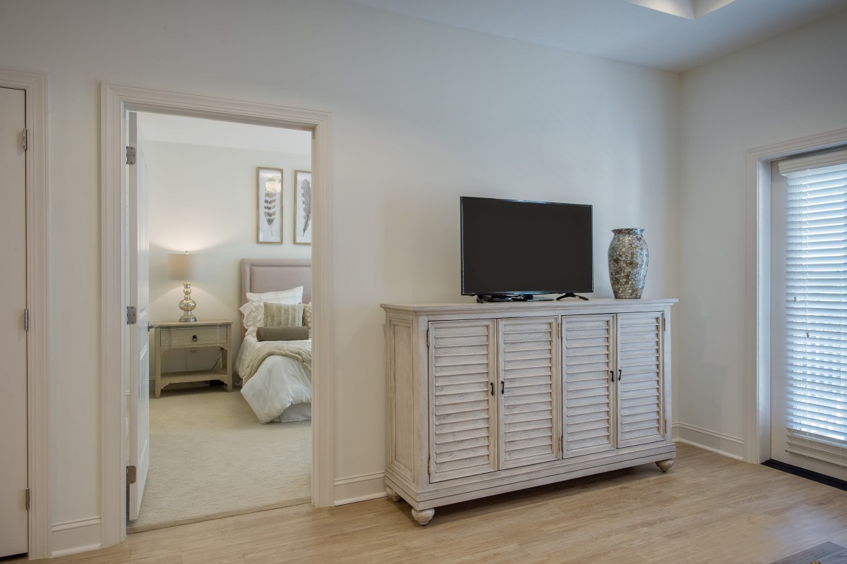 A modern living area featuring a stylish cabinet with a TV, seamlessly connected to a bedroom.