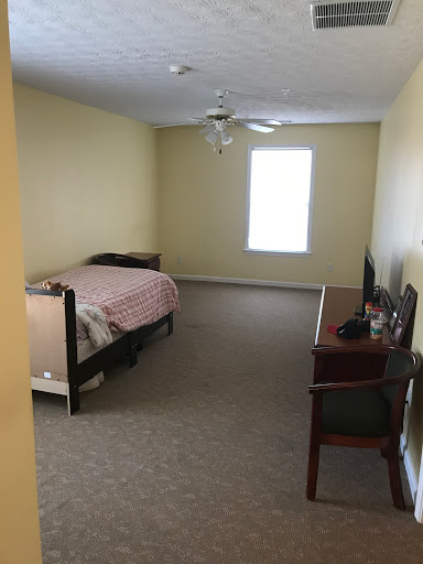 A simple and spacious bedroom with a bed, desk, and window.