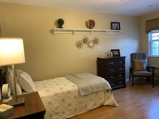 A cozy bedroom with a single bed, soft lighting, and decorative elements on the wall.