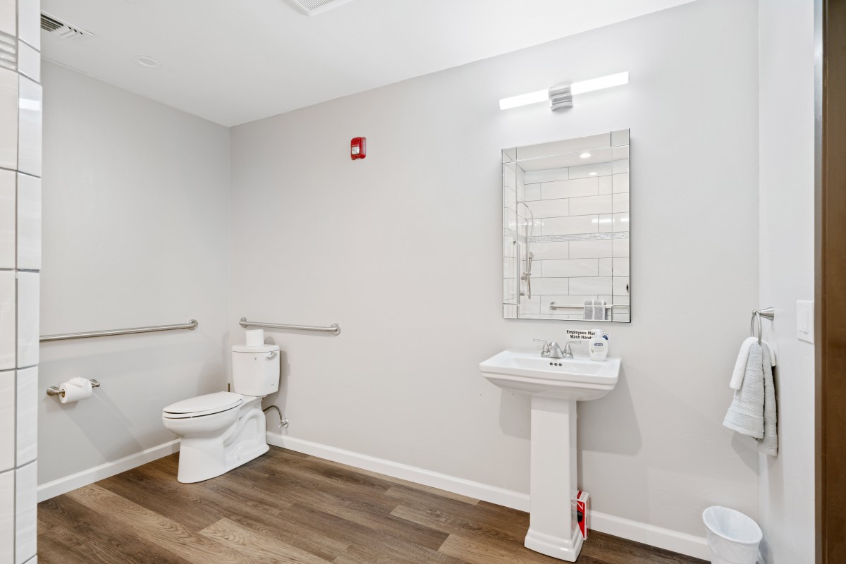 A modern, minimalist bathroom with a toilet, sink, and mirror.