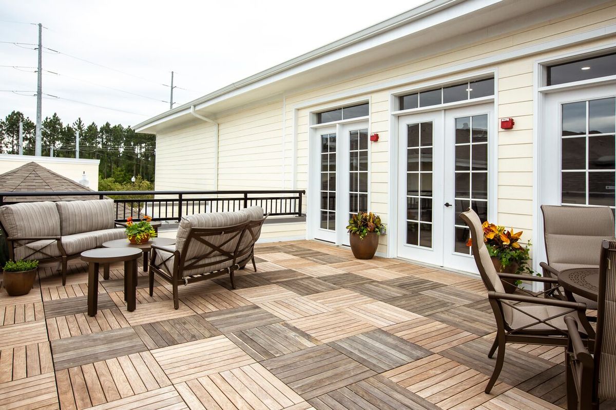 A stylish outdoor patio with wooden tile flooring, featuring comfortable seating and potted plants.
