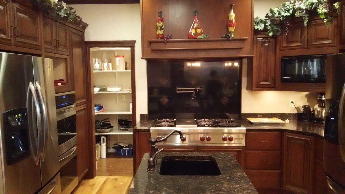A modern kitchen with dark wood cabinets, a stainless steel stove, and a central island sink.