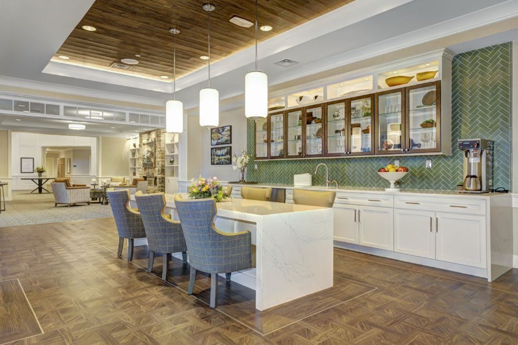 A modern kitchen interior featuring a sleek countertop with blue dining chairs and pendant lighting.
