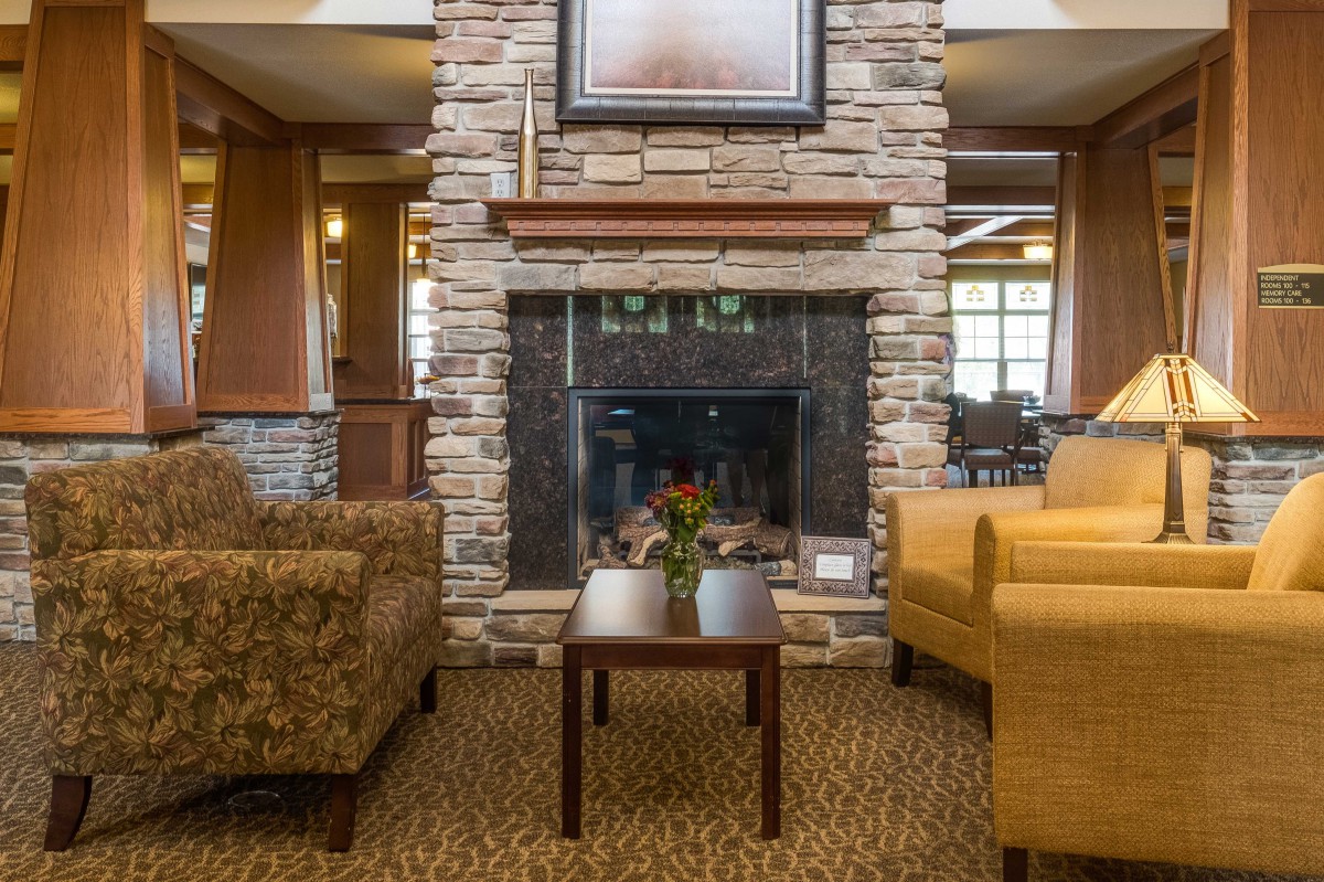 A cozy lounge area featuring a stone fireplace, comfortable seating, and a small table.