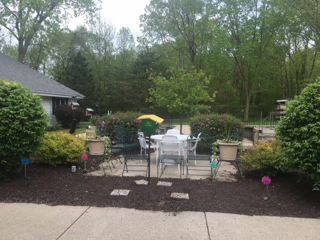 A well-maintained patio area with outdoor furniture surrounded by lush greenery.
