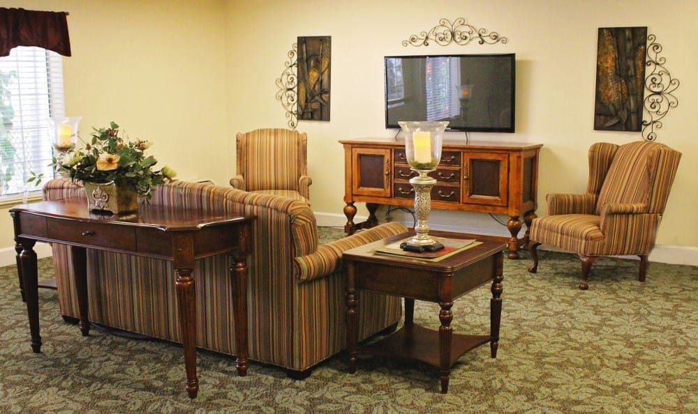A cozy living room with a television, patterned sofa, and wooden furniture.