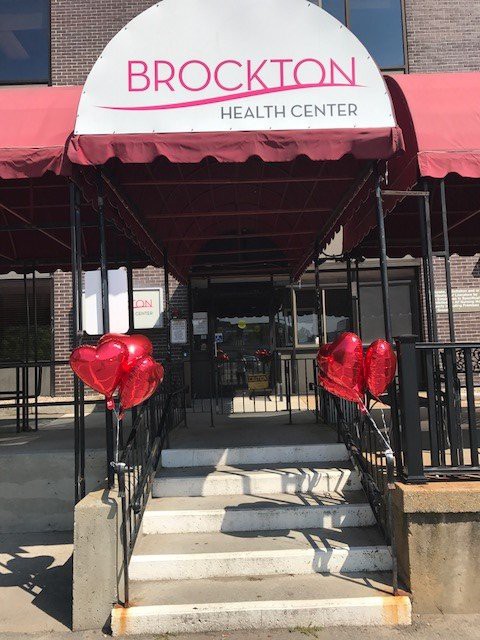 Entrance of a health center with a red awning and heart-shaped balloons.