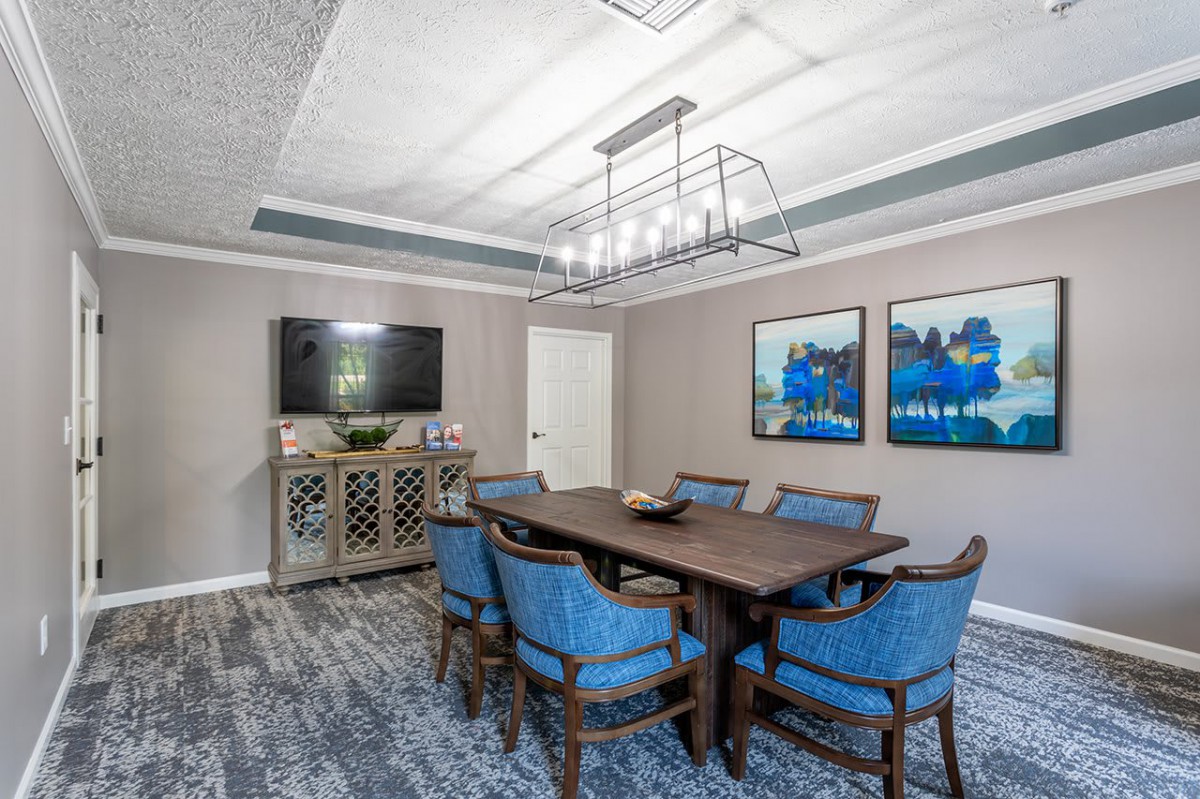 A modern conference room with a large table, blue chairs, and stylish lighting.