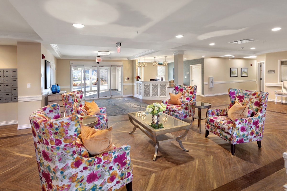 A bright and welcoming lobby area featuring colorful floral chairs and a central glass table.