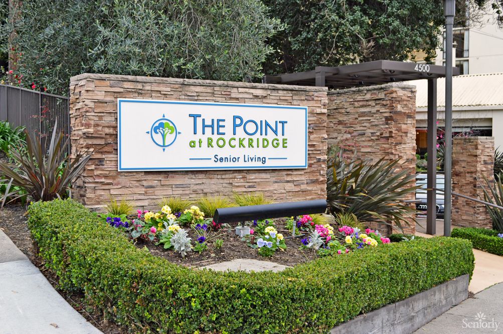 Entrance sign for The Point at Rockridge Senior Living surrounded by well-maintained landscaping and colorful flowers.