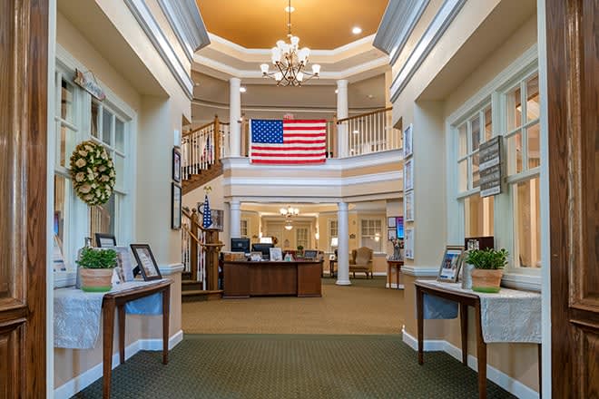 Elegant lobby with a large American flag, chandelier, and welcoming reception area.