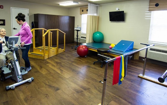 A physical therapy room equipped with various rehabilitation tools such as therapy balls, parallel bars, and resistance bands.