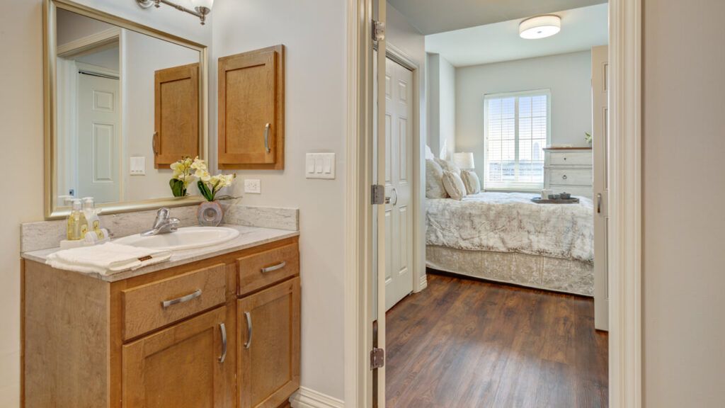 A cozy bedroom and adjoining bathroom with wooden cabinetry and a clean, bright aesthetic.