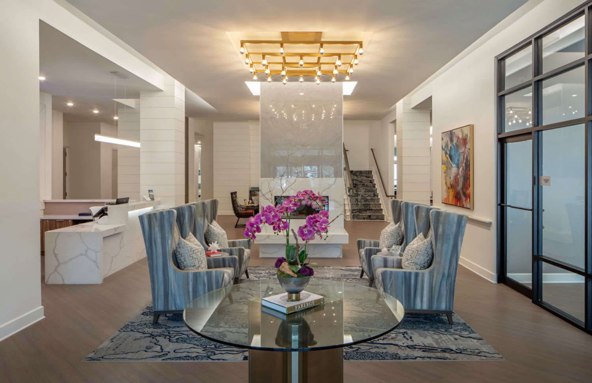 A modern living room with elegant furniture, a striking chandelier, and vibrant artwork.