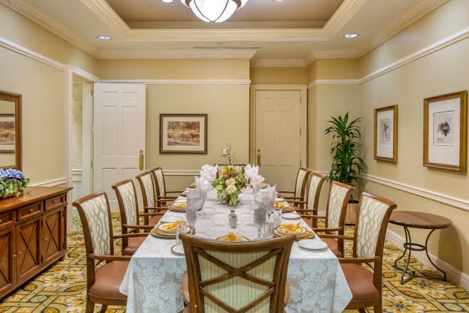A well-decorated dining room with an elegantly set table and chairs, featuring a floral centerpiece and sophisticated lighting.